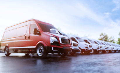 Fleet of commercial vans with a standout red van in front, parked in an organized row under a clear sky